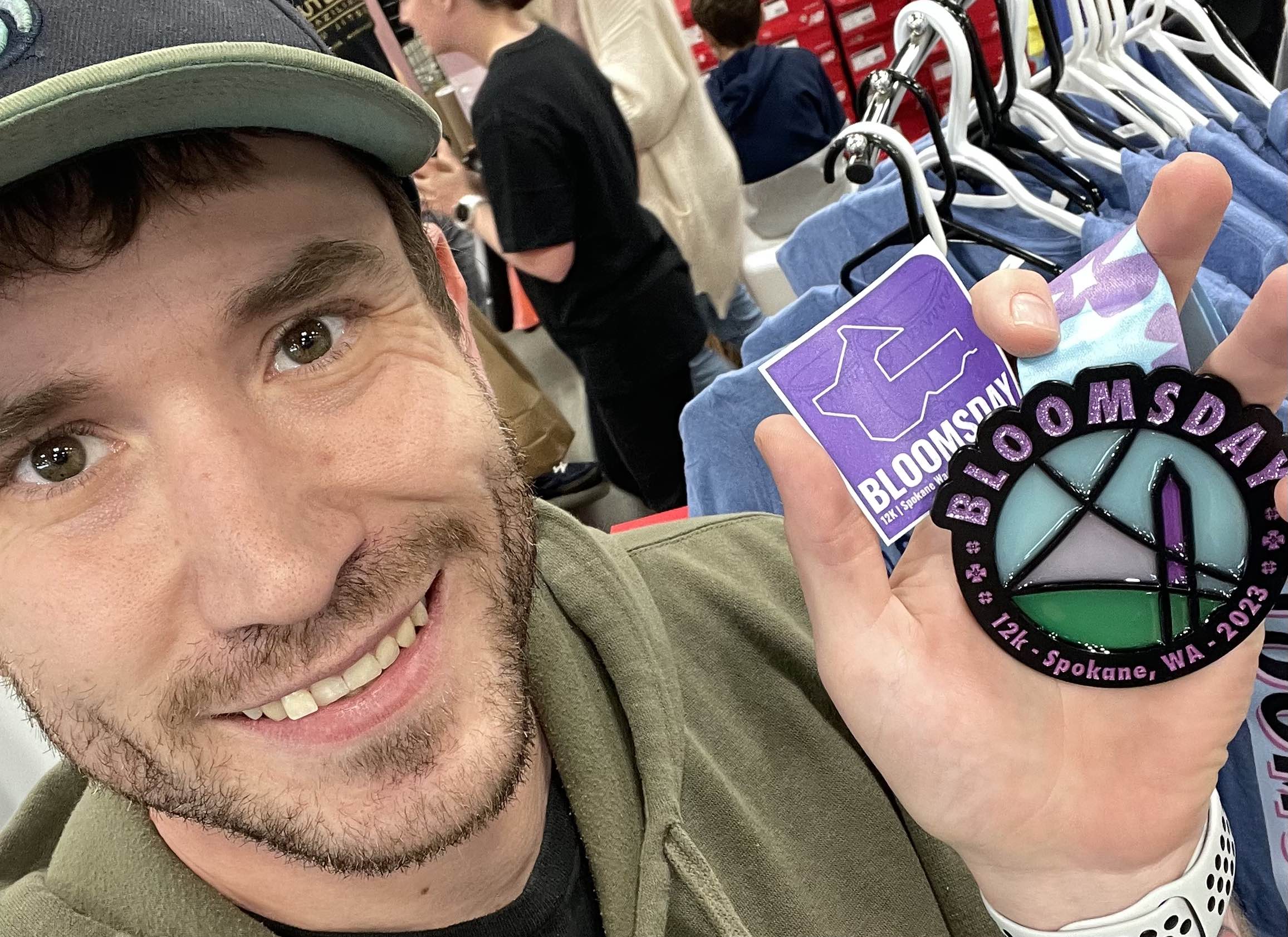 Photo of Gordon Smith holding the medal and sticker he designed for Bloomsday 2023